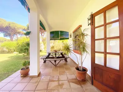a porch with a wooden door and a picnic table at Chalet Roche a 300 metros de la playa in Roche