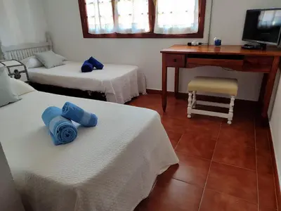 a room with two beds and a desk and a computer at Chalet Roche a 300 metros de la playa in Roche