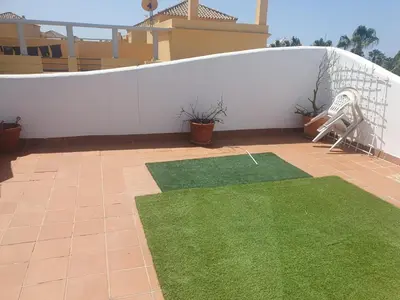 a patio with green grass and a white fence at Bogavante Costa Ballena in Rota