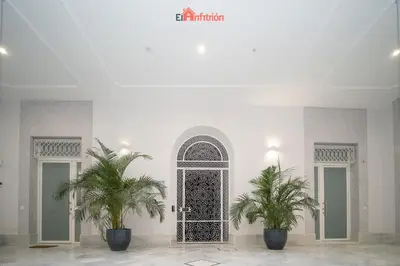 a room with two palm trees in front of a door at El Anfitrión - Argüeso 8 in Sanlúcar de Barrameda