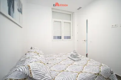 a bed in a white room with a window at El Anfitrión - Argüeso 8 in Sanlúcar de Barrameda