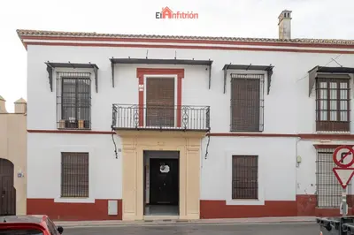 a white building with a black door and windows at El Anfitrión - Mirador en casco antiguo con parking in Sanlúcar de Barrameda