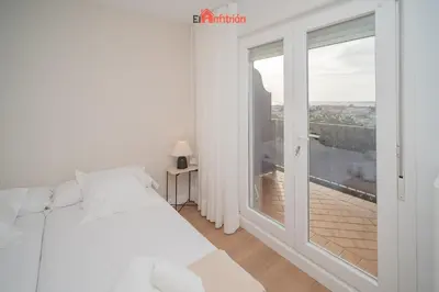 a bedroom with a bed and a large window at El Anfitrión - Mirador en casco antiguo con parking in Sanlúcar de Barrameda