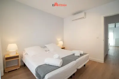 a bedroom with a white bed with towels on it at El Anfitrión - Mirador en casco antiguo con parking in Sanlúcar de Barrameda