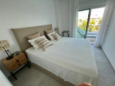 a bedroom with a large white bed and a window at Costa Ballena & Eleven Lights in Chipiona