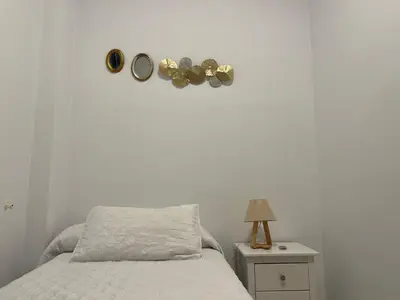 a bedroom with a bed and a table with a lamp at Rodmar Playa Grupo AC Gestion in Cádiz