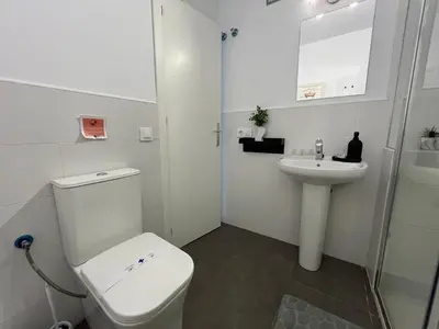 a white bathroom with a toilet and a sink at Rodmar Playa Grupo AC Gestion in Cádiz