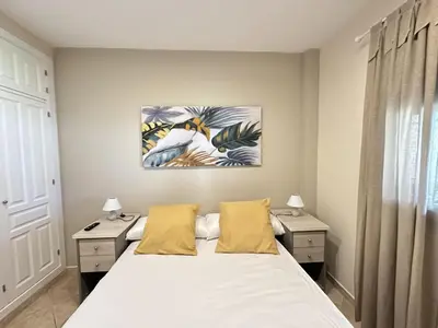a bedroom with a white bed and two night stands at Apartamentos Chiclana Chalet Carboneros in Chiclana de la Frontera