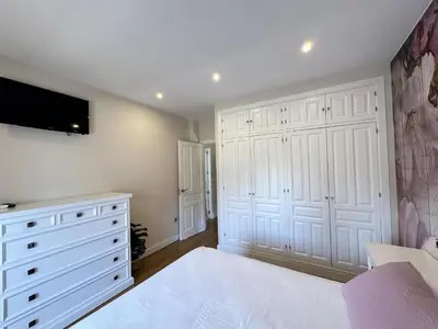 a bedroom with white cabinets and a tv on the wall at Apartamentos Chiclana Chalet Carboneros in Chiclana de la Frontera