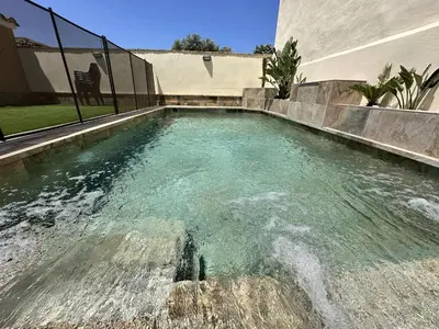 a swimming pool with blue water in front of a house at Apartamentos Chiclana Chalet Carboneros in Chiclana de la Frontera