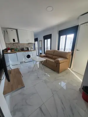 a kitchen and living room with a couch and a table at Apartamento Gloria Bendita in Jerez de la Frontera