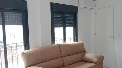 a couch in a living room with two windows at Apartamento Gloria Bendita in Jerez de la Frontera