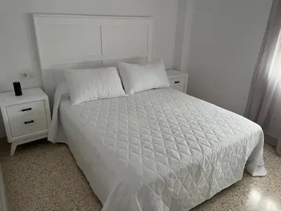 a bedroom with a white bed and two night stands at Casa Gran Cinema in Sanlúcar de Barrameda
