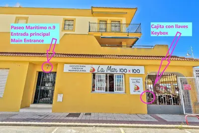 a yellow building with pink signs on the side of it at Beachfront Duplex 1ª línea & Terraces Oceanfront in El Puerto de Santa María
