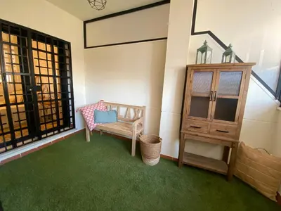 a room with a chair and a cabinet and green carpet at El Paraíso de Fuentebravía - Primera Línea de Playa in El Puerto de Santa María