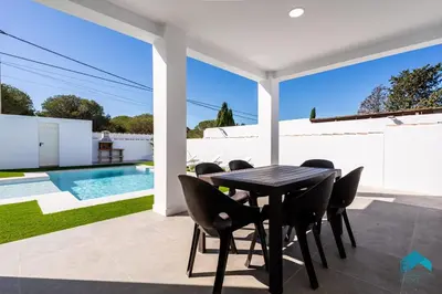 a patio with a table and chairs and a swimming pool at Villa Granizo C in Chiclana de la Frontera