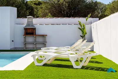 a group of chairs sitting on the grass next to a pool at Villa Granizo C in Chiclana de la Frontera