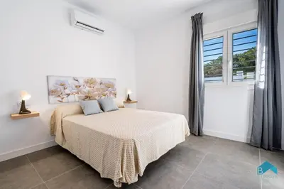 a white bedroom with a bed and a window at Villa Granizo C in Chiclana de la Frontera