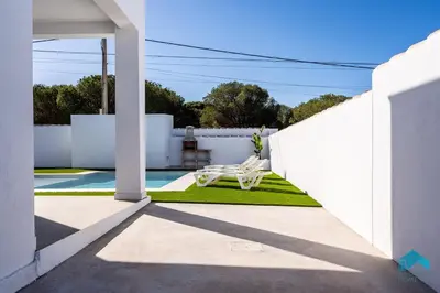 a patio with a white chair and a pool at Villa Granizo C in Chiclana de la Frontera
