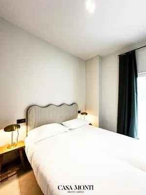 a bedroom with a large white bed and a window at Casa Monti - Sherry Suites A in Jerez de la Frontera