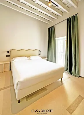 a white bed in a room with green curtains at Casa Monti - Sherry Suites A in Jerez de la Frontera