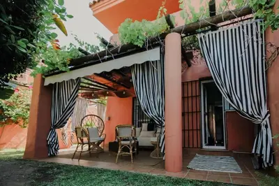 an outdoor patio with awning and chairs and tables at Casa de lujo en Las Redes in El Puerto de Santa María