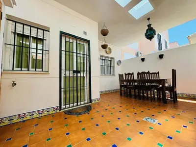 an empty room with a table and chairs and windows at Casa Familiar- Residencial Solmar in Sanlúcar de Barrameda