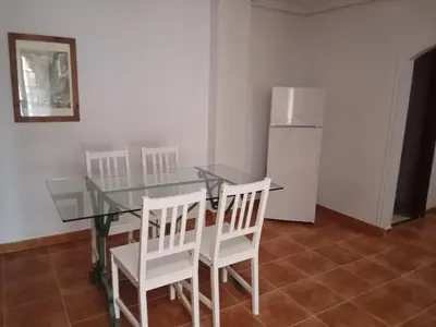 a kitchen with a glass table and white chairs and a refrigerator at Apartamentos Jasmund - Bungalow 117 in San Fernando
