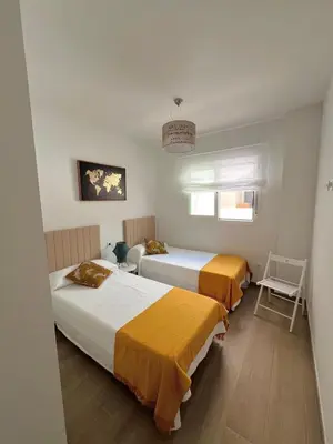 a bedroom with two beds and a chair at Apartamento en Costa Ballena in Chipiona