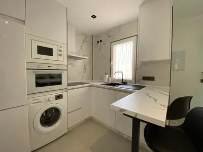 a white kitchen with a washing machine and a sink at Playa La Barrosa, AlojamientosLola in Chiclana de la Frontera