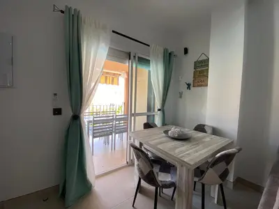 a dining room with a table and chairs and a sliding glass door at Playa La Barrosa, AlojamientosLola in Chiclana de la Frontera