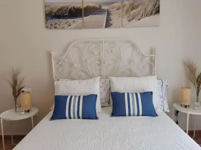 a bedroom with a white bed with blue and white pillows at Precioso apartamento en Rota in Rota