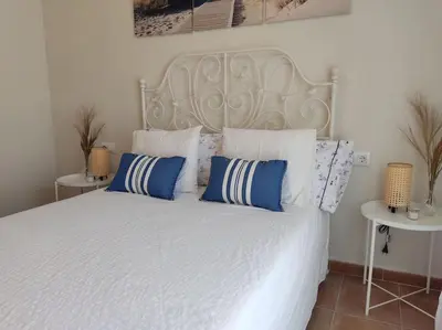 a bedroom with a white bed with blue and white pillows at Precioso apartamento en Rota in Rota