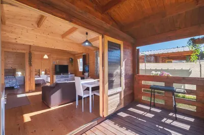 a wooden cabin with a balcony with a desk and a bedroom at Bungalow Luna in Chiclana de la Frontera