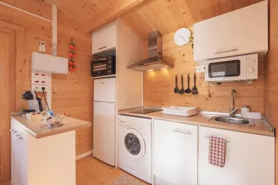 a kitchen with white appliances and wooden walls at Bungalow Luna in Chiclana de la Frontera