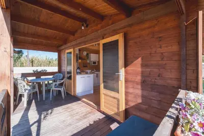 a wooden house with a deck with a table at Bungalow Luna in Chiclana de la Frontera