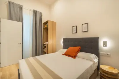 a bedroom with a bed with an orange pillow on it at Urania Cadiz Apartments by Soho Boutique in Cádiz
