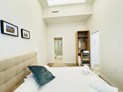 a bedroom with white walls and a bed with a blue pillow at Urania Cadiz Apartments by Soho Boutique in Cádiz