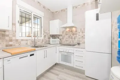 a white bedroom with a bed and a mirror at Poniente in Chiclana de la Frontera