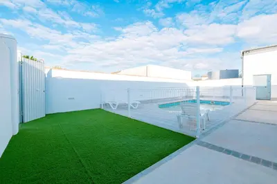 a swimming pool on the side of a building with green grass at Poniente in Chiclana de la Frontera