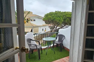 a balcony with chairs and a table on the grass at La Barrosa Beach Holiday Home By ChiclanaDreams in Chiclana de la Frontera