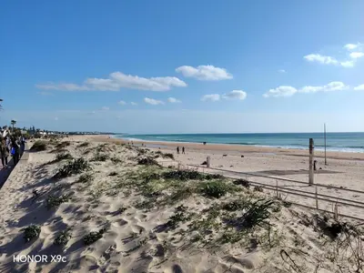 a group of people walking on the beach at La Barrosa Beach Holiday Home By ChiclanaDreams in Chiclana de la Frontera