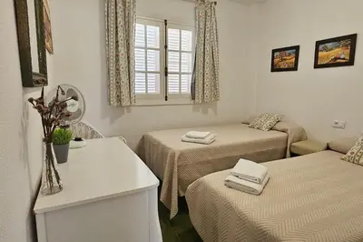 a small room with two beds and a window at La Barrosa Beach Holiday Home By ChiclanaDreams in Chiclana de la Frontera