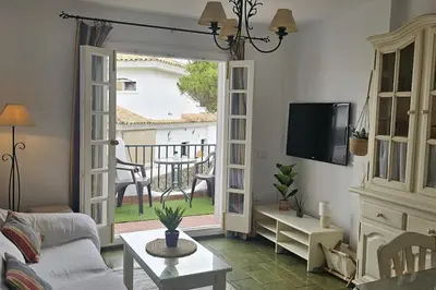 a living room with a couch and a tv and a table at La Barrosa Beach Holiday Home By ChiclanaDreams in Chiclana de la Frontera