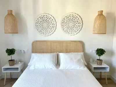 a bedroom with a bed with white sheets and pendant lights at La Buganvilla in Chiclana de la Frontera