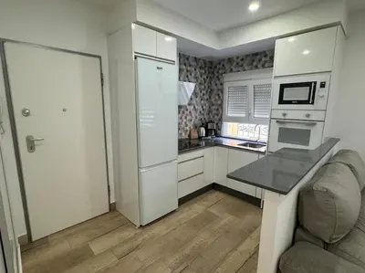 a kitchen with white cabinets and a table and a couch at El Refugio de Susana Grupo AC Gestion in Cádiz