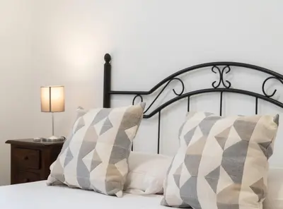 a bed with two pillows and a lamp on a table at Apartoyou - Sol y Playa Goleta in El Puerto de Santa María