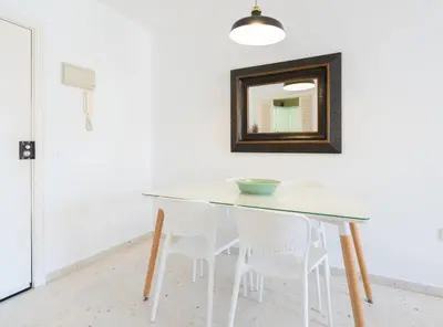a dining room table with white chairs and a mirror at Apartoyou - Sol y Playa Goleta in El Puerto de Santa María