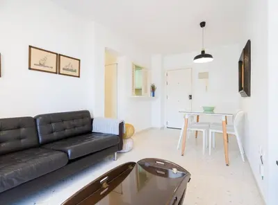 a living room with a black couch and a table at Apartoyou - Sol y Playa Goleta in El Puerto de Santa María