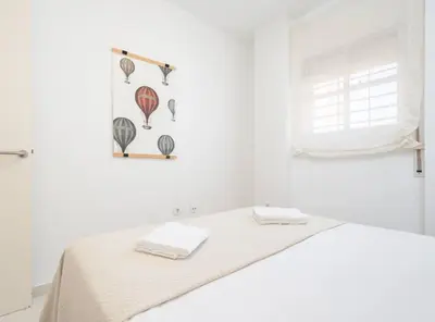 a white room with a bed with two towels on it at Apartoyou - Sol y Playa Goleta in El Puerto de Santa María